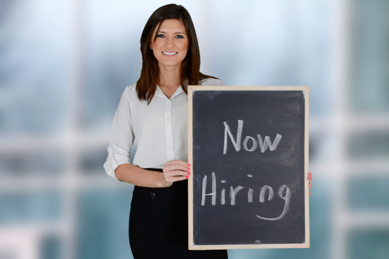 A woman holding up a sign that says " now hiring ".