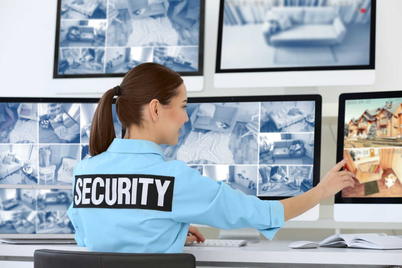 A security guard sitting at her desk in front of multiple monitors.